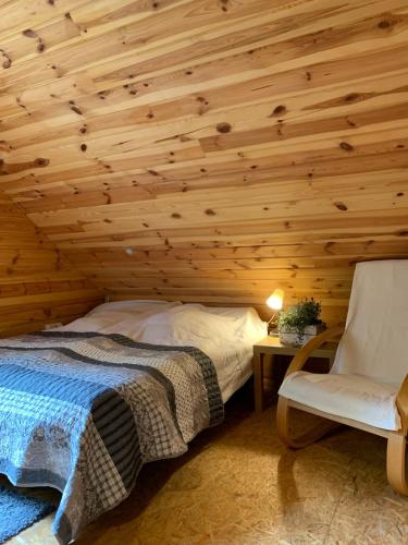a bedroom with a wooden ceiling with a bed and a chair at DOM w BORACH in Cekcyn