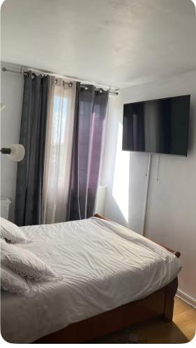 a bedroom with a bed with a television on the wall at chambre Cosy et Chambre Sam in Rosny-sous-Bois
