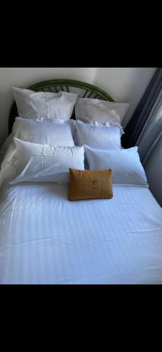 a white bed with white pillows and a brown pillow at chambre Cosy et Chambre Sam in Rosny-sous-Bois