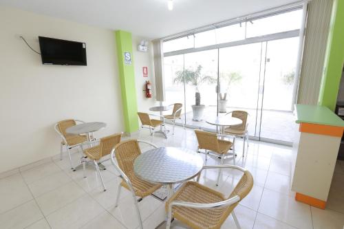 a dining room with tables and chairs and a tv at Hostal Florida in Chiclayo