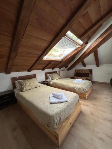 two beds in a attic room with a skylight at APARTAHOTEL CANFRANC in Canfranc