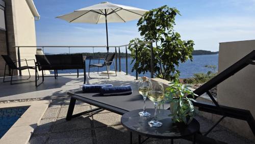 a patio with a table with wine glasses and an umbrella at Villa Vista in Blato