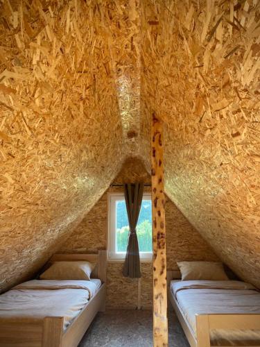 two beds in a room with a straw roof at Villageescape in Cetinje