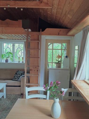 a living room with a table and a couch and windows at Cozy Cabin near Balka Beach with outdoor toilet and kitchen in Neksø
