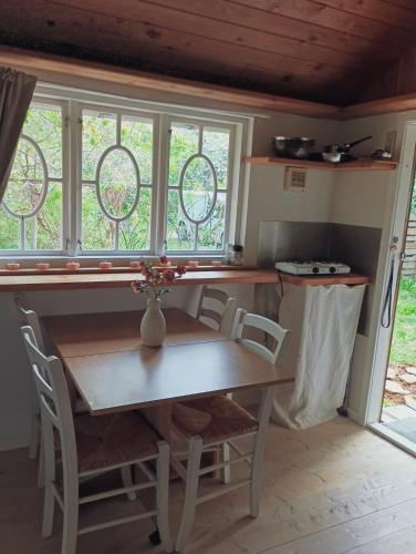 a table and chairs in a kitchen with windows at Cozy Cabin near Balka Beach with outdoor toilet and kitchen in Neksø
