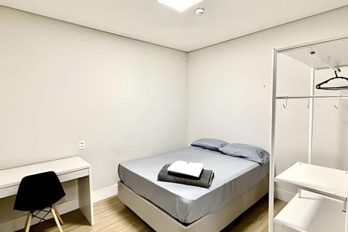 a white bedroom with a bed and a mirror at Quartos individuais vila olimpia in São Paulo