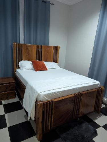 a bed with a wooden headboard in a bedroom at Eden Vista Stays in Dar es Salaam