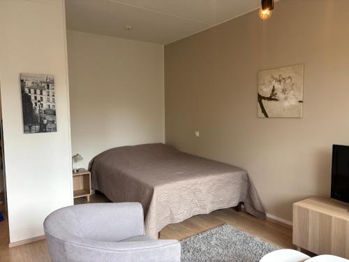 a bedroom with a bed and a chair and a television at Mirella in Tampere