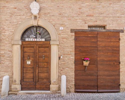 a building with a wooden door and a basket of flowers at Antica Dimora Sforza Bed & Bike in Corinaldo