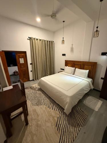 a bedroom with a large white bed and a desk at Swiss Bay Hotel & Resort-Arugambay in Pottuvil