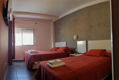 a hotel room with two beds with red sheets at Hotel Cafayate Design in Cafayate