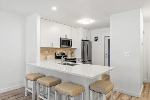 a white kitchen with a sink and stools at Bright 2BR Oceanview Condo in Key West