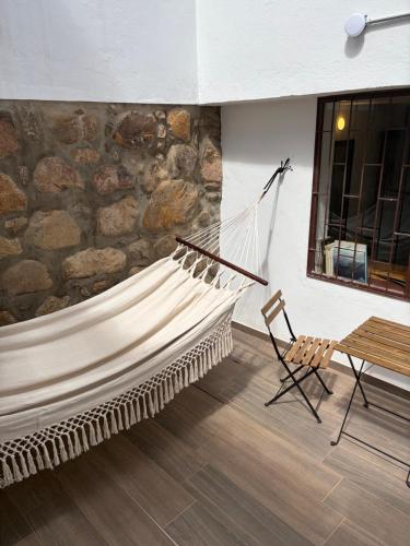a hammock and a chair in a room with a stone wall at Hostel Once Once in Villa de Leyva