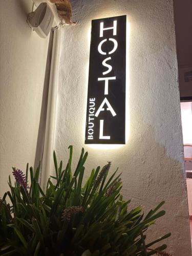 a sign on the side of a wall with a plant at Hostel Once Once in Villa de Leyva