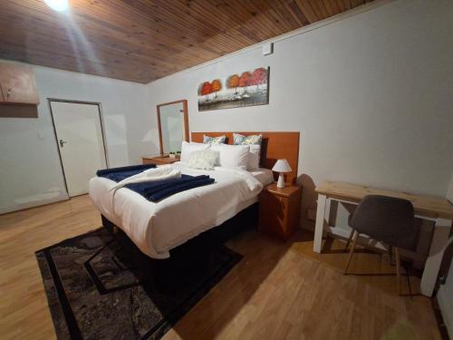a bedroom with a bed and a desk with a chair at Le Cape Nest Guest House in Parow