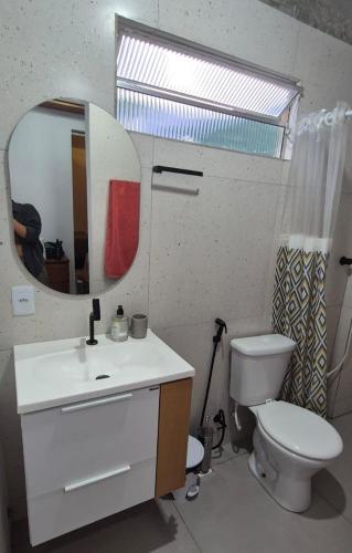 a bathroom with a toilet and a sink and a mirror at Estúdio aconchegante com cozinha externa e quintal in Morro do Chapéu