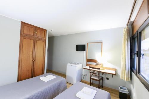 a room with two beds and a desk and a mirror at São Roque Suites in Bragança