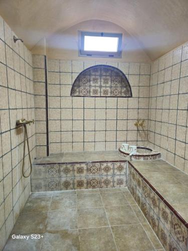 a tiled bathroom with a shower with a window at Villa du bonheur Chambres d'hote in Ouled el guerne