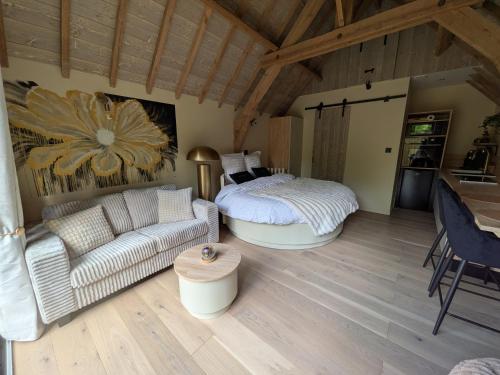 a living room with a bed and a couch at Domaine du Bois l'Abbé - Le Nid in Saint-Martin-Boulogne