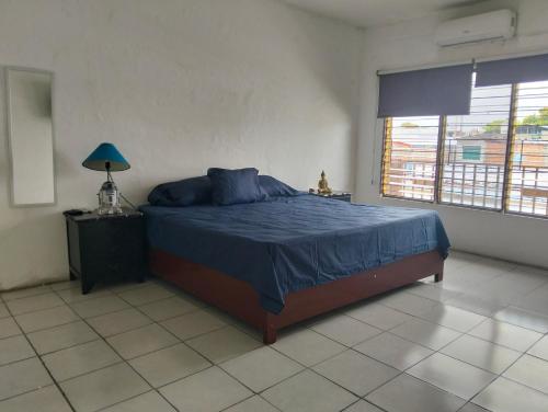 a bedroom with a bed with blue sheets and a window at Tu hogar en tapachula in La Concepción