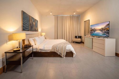 a bedroom with a bed and a desk and a television at Luxury 3BR Beachfront Private Pool Ultravioleta in Cabarete