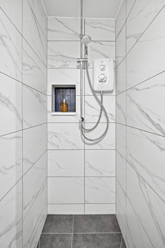 a bathroom with a shower with white marble walls at Corran House Guest House in Oban