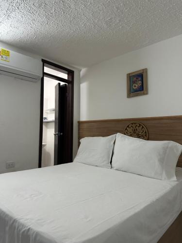 a bedroom with a bed with white sheets and a window at Edificio Don Ramon in Valledupar