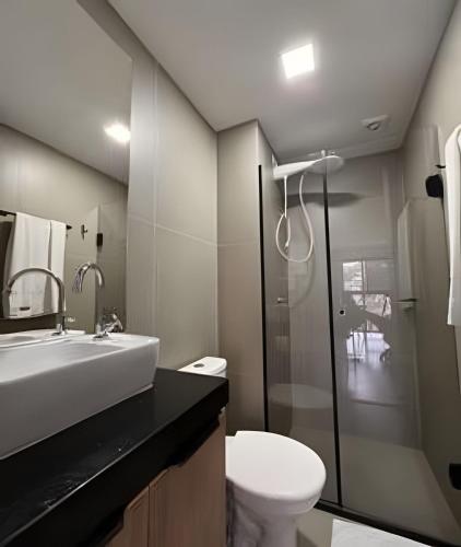 a bathroom with a sink and a toilet and a shower at Suporte VIP: TOPstudio no Centro c/Piscina Jacuzzi in Poços de Caldas