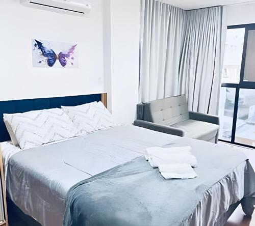 a bedroom with a large bed and a chair at Suporte VIP: TOPstudio no Centro c/Piscina Jacuzzi in Poços de Caldas