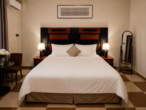 a bedroom with a large white bed and two lamps at شقق عناوين الفخامة in Şāmitah