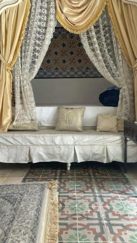 a bed in a room with curtains and a rug at Beit Khalifa in Kairouan