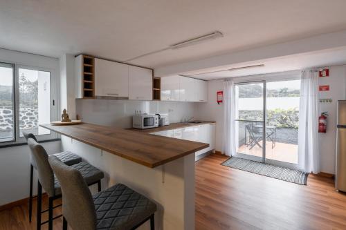 a kitchen with white cabinets and a counter with chairs at Casa Dos Arcos Oceanfront Apartments in Arcos