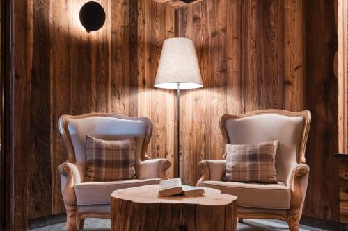 zwei Stühle, ein Tisch und eine Lampe in einem Zimmer in der Unterkunft Chalet Barbara in Arabba