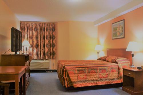 a hotel room with a bed and a desk at Aurora Park Inn & Suites in Dawson Creek