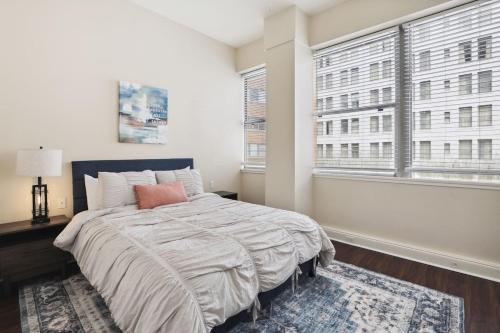 a bedroom with a large bed and two windows at Suite Bleu 5 Min walk to Bourbon st Rooftop Pool in New Orleans