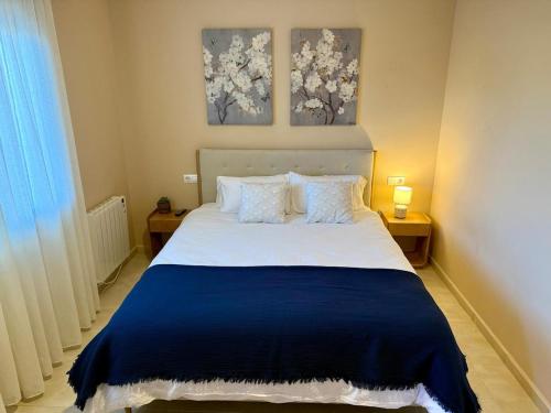 a bedroom with a large bed with two paintings on the wall at Apartmento Las Palmeras in Noalla
