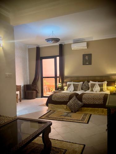 a bedroom with two beds and a large window at Hotel tafoukt in Marrakesh