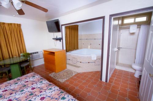 een badkamer met een bad, een bed en een wastafel bij Mission Bell Motel in Ventura