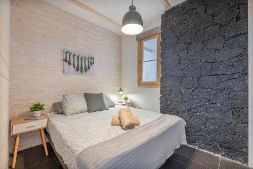 a bedroom with a bed and a stone wall at Suite Junior Amanecer in Mácher