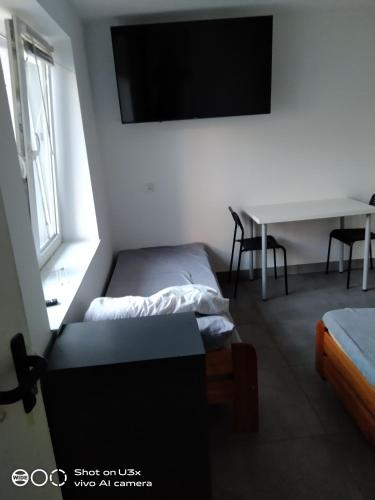 a bedroom with a bed and a desk and a tv at Noclegi Tuszyn S in Tuszyn