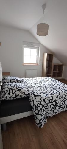 a bedroom with a bed with a black and white blanket at Le Point Relais in Fumay