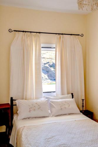 a bed with white pillows in front of a window at Demetra Waterfront House-Authentic Syros, by Elefthia Syros in Megas Gialos - Nites