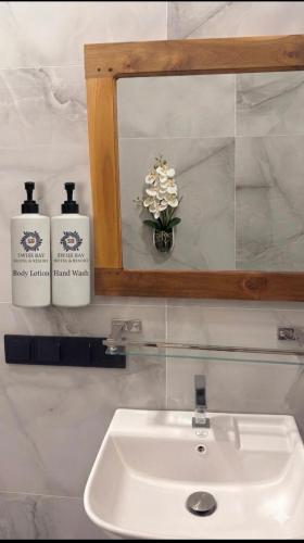 a bathroom sink with a mirror and two soap dispensers at Swiss Bay Hotel & Resort-Arugambay in Pottuvil