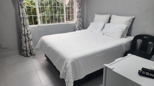 a bedroom with a white bed and a window at S-and Kasa Guest House in Pietermaritzburg