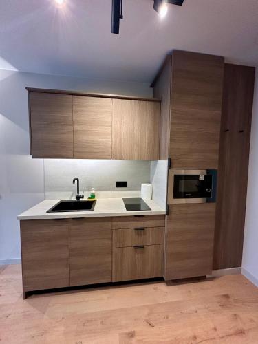 a kitchen with wooden cabinets and a sink and a microwave at Eleve Residences - Sand Studio in Sofia