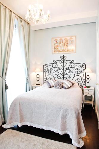 - une chambre dotée d'un lit blanc avec deux lampes et un lustre dans l'établissement La Charme Du Marais, à Paris