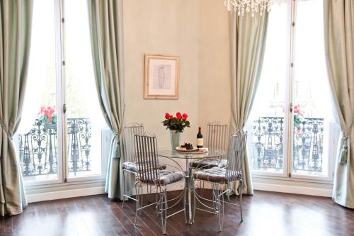 une salle à manger avec une table, des chaises et des fenêtres dans l'établissement La Charme Du Marais, à Paris