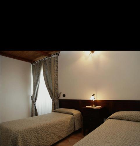 a bedroom with two beds and a table and a window at hotel il ghiro in Ovindoli