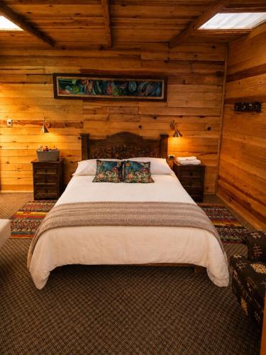 a bedroom with a large bed with wooden walls at Chalet Magico en el Bosque in Oicatá
