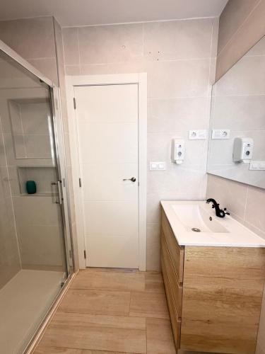 a bathroom with a sink and a shower and a door at Brisas del mar in Faro de Cullera